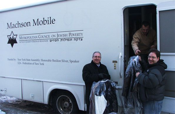 Assemblyman Cymbrowitz helping Madelaine Cleaners’ owner, Eric Lederman, load winter coats onto Met Council’s Machson Mobile for distribution to the needy.