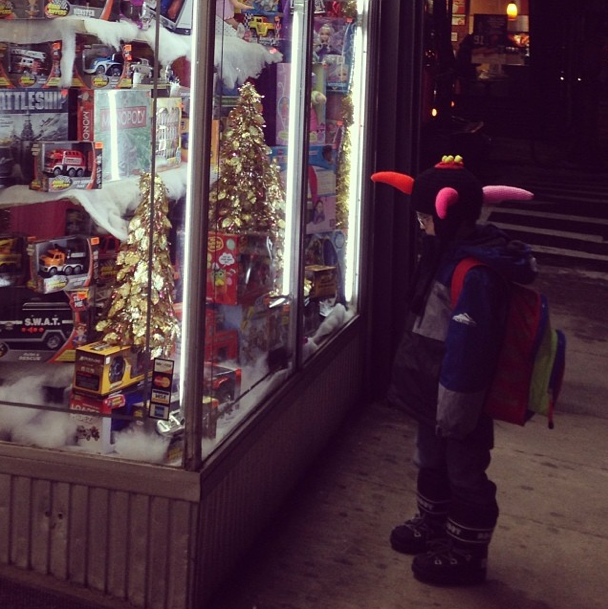 Kid looking at toys in window of Save on Fifth