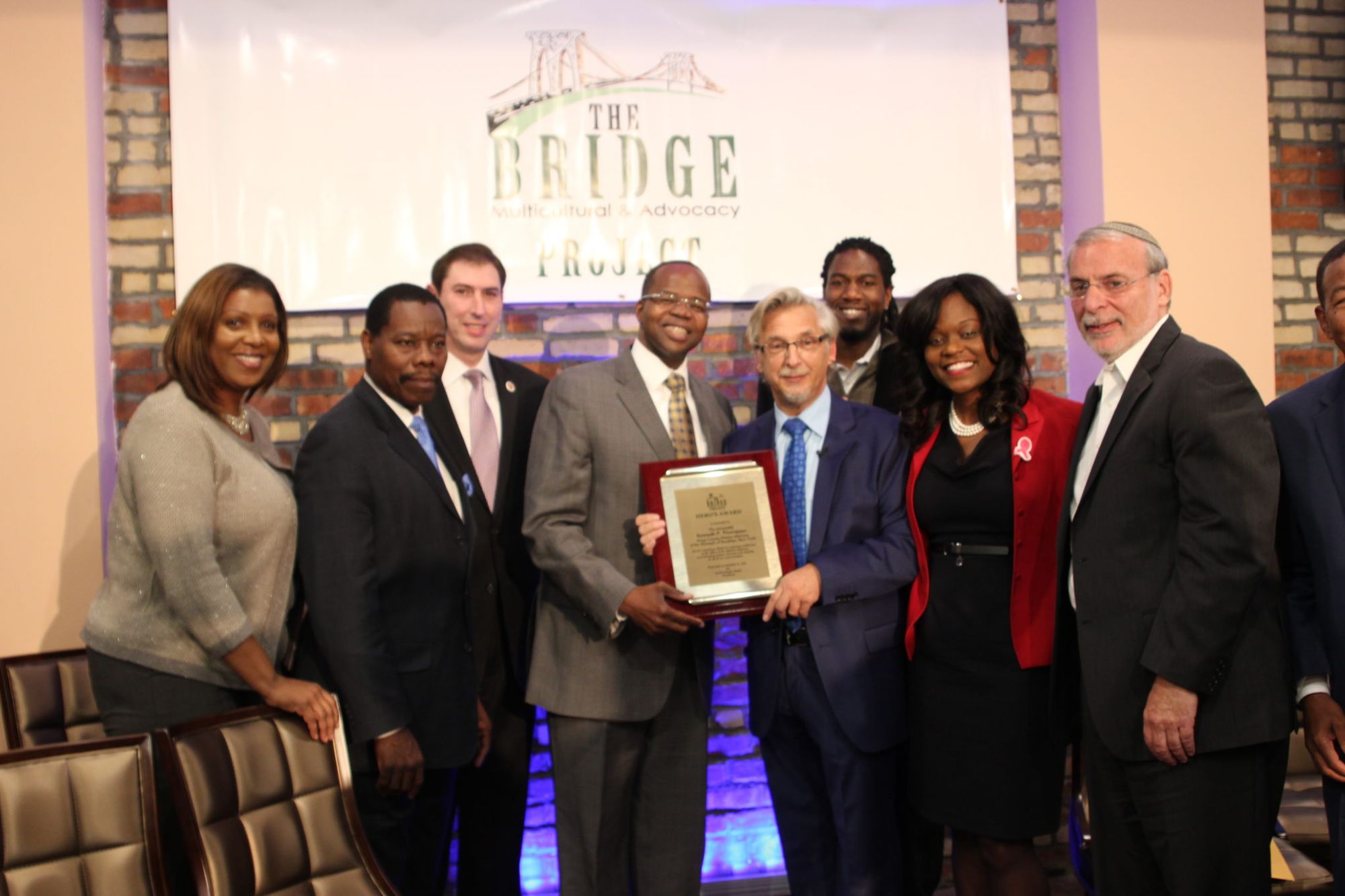 Local politicians and community advocates pose as Brooklyn District Attorney Kenneth Thompson accepts his Hero Award from Mark Meyers Appel at the Bridge Community Center grand opening. 