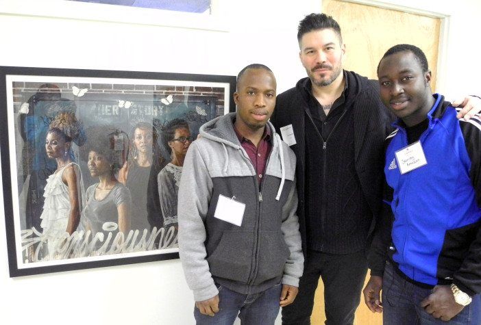 Artist Tim Okamura, center, is pictured with Adult Literacy Center students Moussa Barry , left, and Stanley Amazan next to a print of "Her Story." Photo courtesy CAMBA