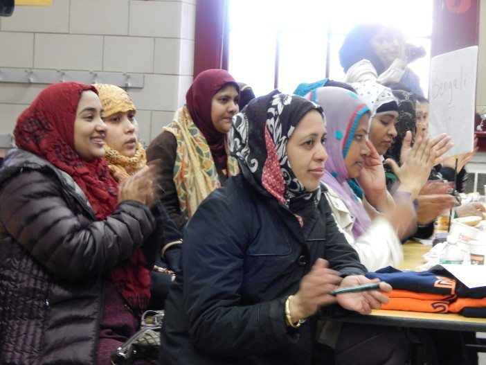 Parents at the Bengali table clap as school leaders discuss the healthier food.