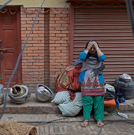 A woman stands outside her home in Bhaktapur, Kathmandu Valley after the earthquake. Photo via UNICEF.