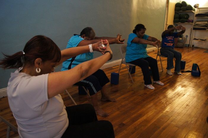 Seniors do chair yoga at Move With Grace. (Photo by Rebeca Ramirez / Myrtle Avenue Brooklyn Partnership)