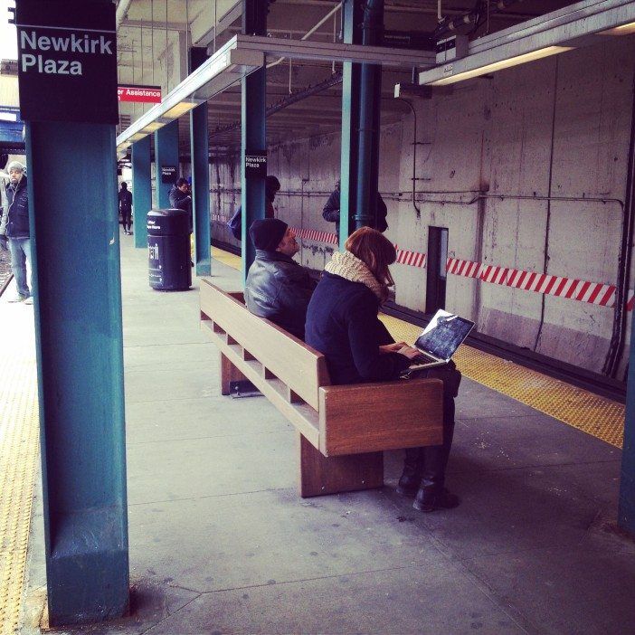 woman uses laptop on subway station platform