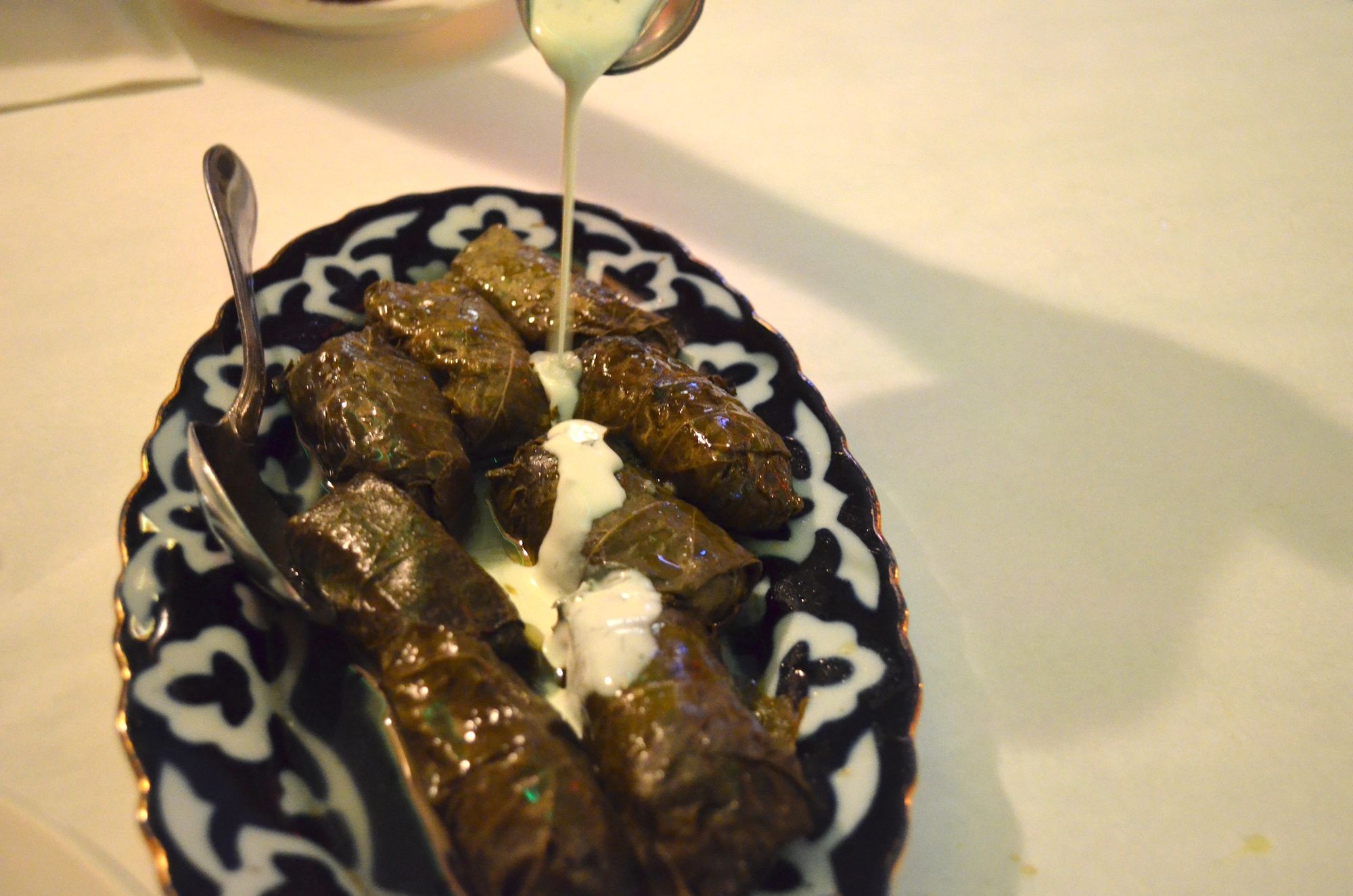 Pouring the white sauce onto the stuffed grape leaves.