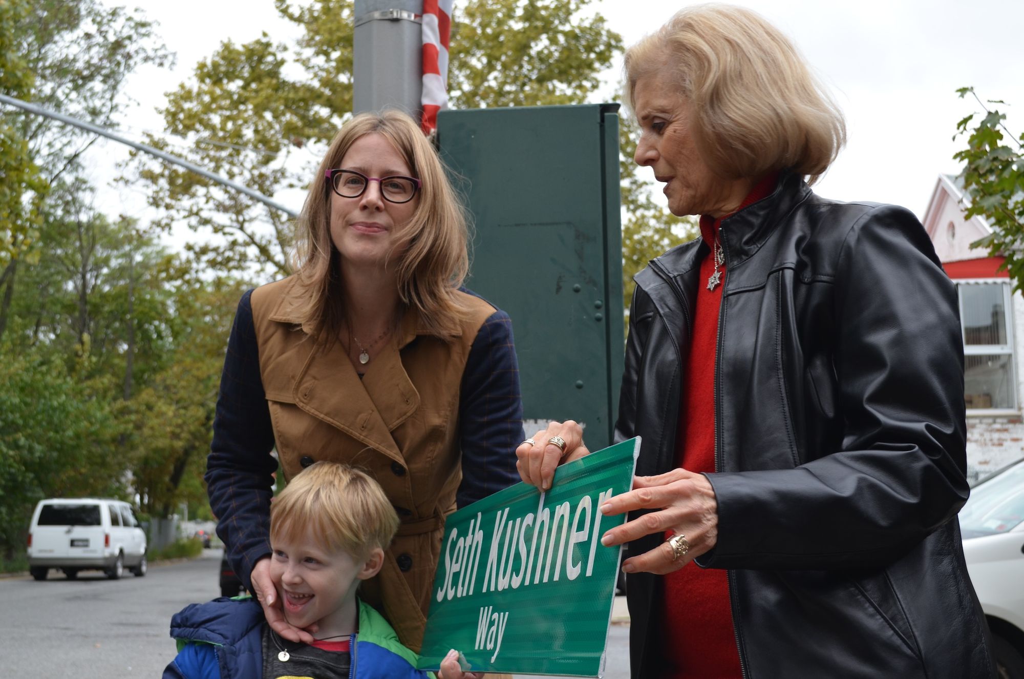 Seth Kushner's wife Terra (Left), with their son Jackson, holding the new street sign with Seth's mom, Linda.