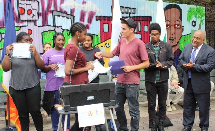 Artist Damien Mitchell hands out certificates to students who worked on the mural. (Photo by Shannon Geis/Ditmas Park Corner)