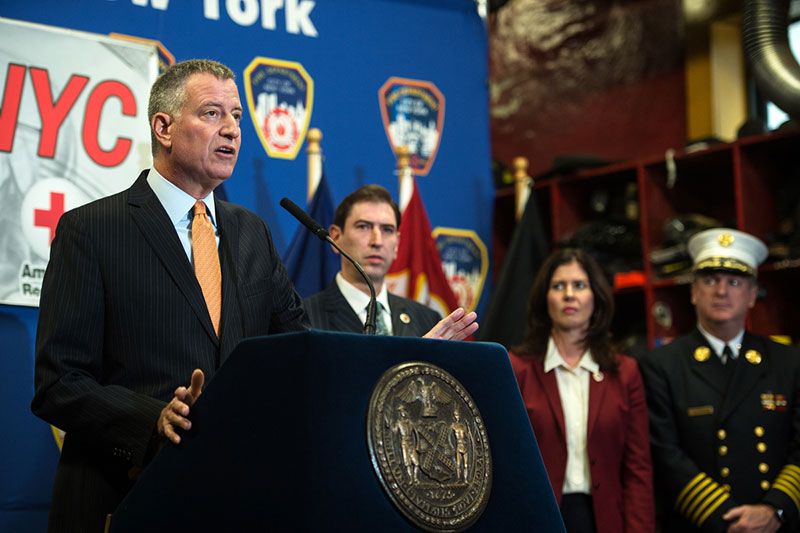 Mayor Bill de Blasio speaking about the launch of #GetAlarmedNYC. City Councilman Chaim Deutsch stand behind the mayor.