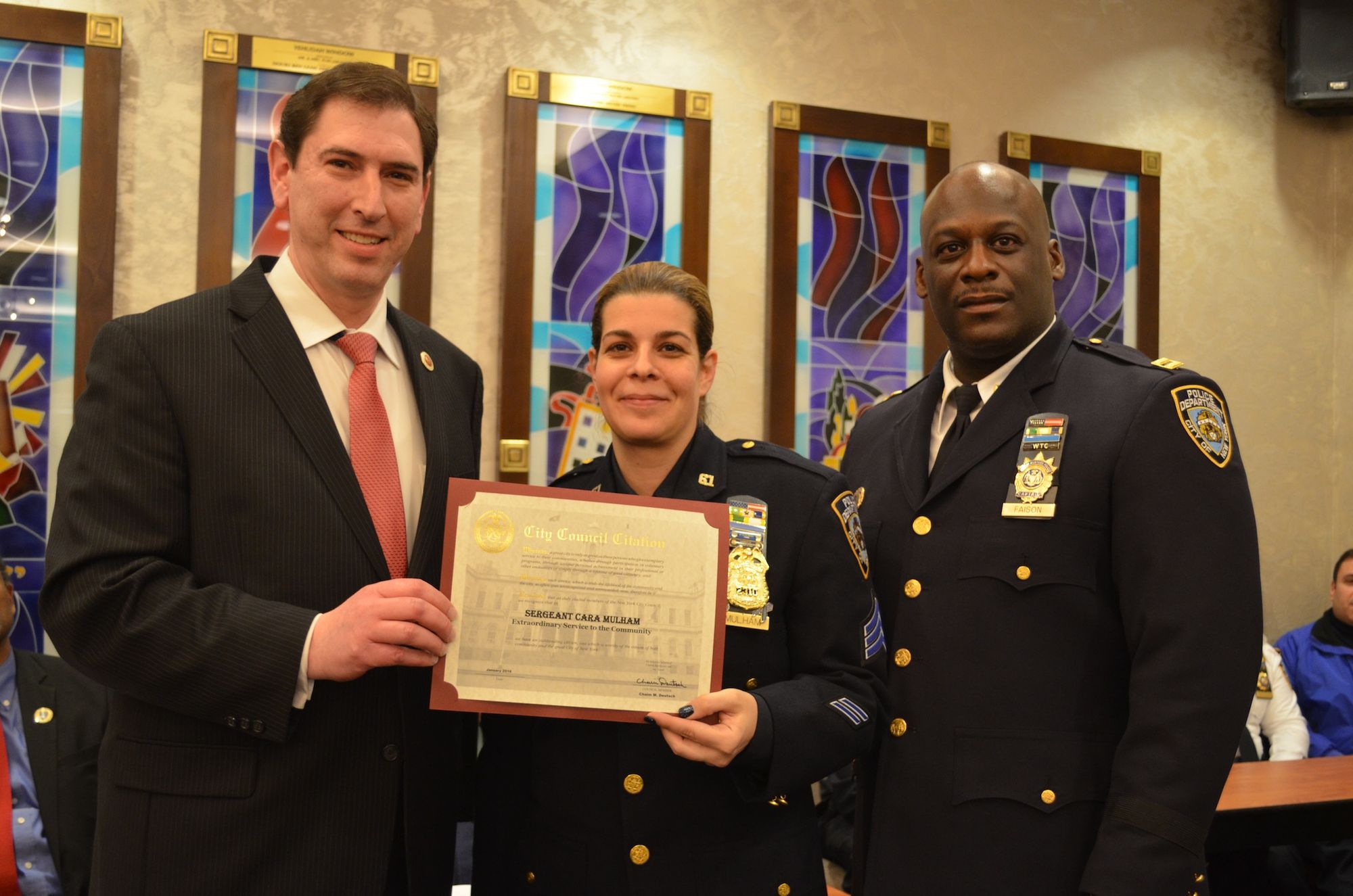 Sergeant Cara Mulham standing between City Councilman Chaim Deutsch, left, and Captain Winston Faison.