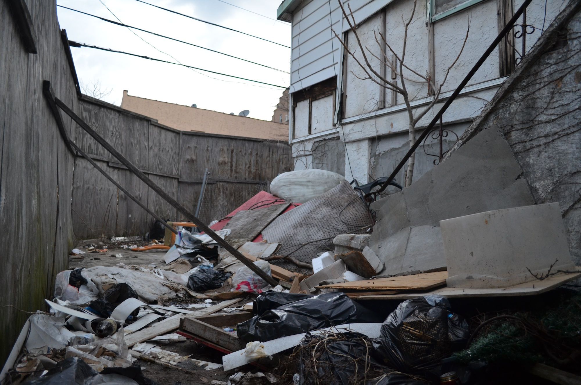 Trash piles up behind the wooden walls around the property. (Photo: Alex Ellefson / Sheepshead Bites)