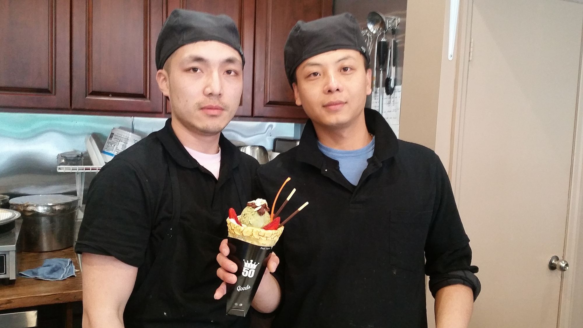 Manager Ricky Chen, on the right, and employee Ben pose with one of the crepe concoctions. (Photo by Heather Chin/Sunset Park Voice)