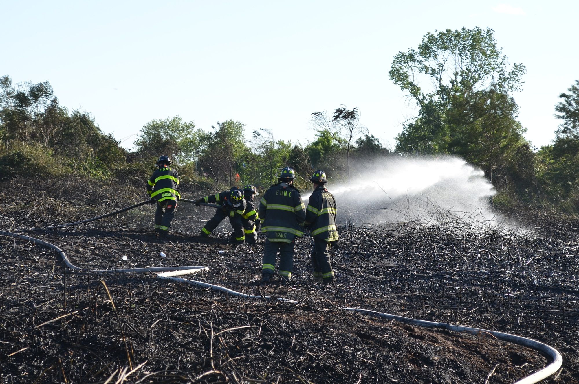 Firefighters dousing the last smokey pockets of Sunday's brush fire. (Photo: Alex Ellefson / Sheepshead Bites)