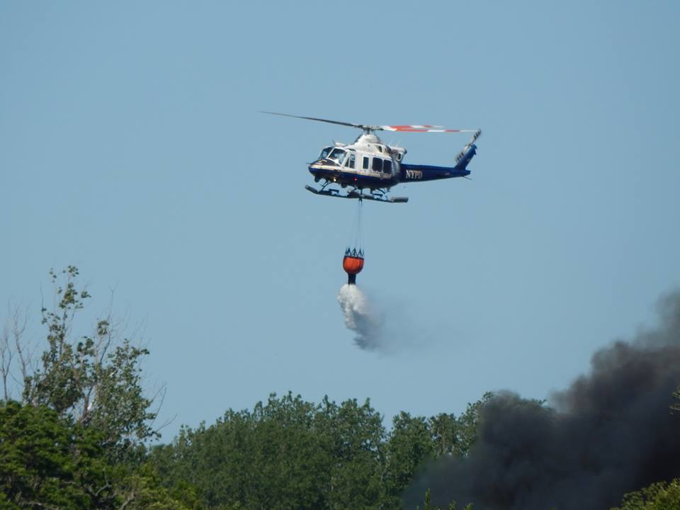 A police helicopter using a " bambi bucket" to drop water on the flames. (Photo: Mike Wright / Facebook)