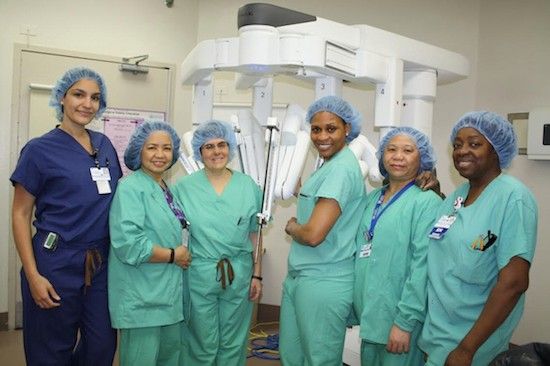 NYU Lutheran's Robotic Surgery Team: Left to Right: Dr. Lisamarie Colon-Ramirez, Merilyn Regollo, Dr. Diana Contreras,, Natacha Cohen, Agnes Diamante and Dianna Norman with the robotic surgery system. (Courtesy: NYU Lutheran Medical Center)